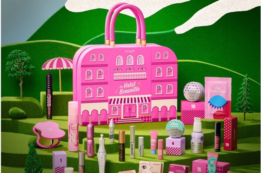 The Benefit Hotel Beneville Advent Calendar 2026, a pink hotel-shaped case on a green hillside set, surrounded by its mascaras, blushes and brow products