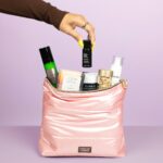 The Caroline Hirons Collagen Support Kit pink kit bag with its six products coming out of it on a lilac background