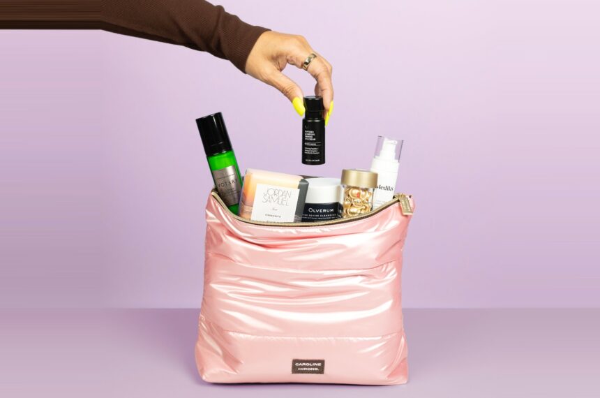 The Caroline Hirons Collagen Support Kit pink kit bag with its six products coming out of it on a lilac background