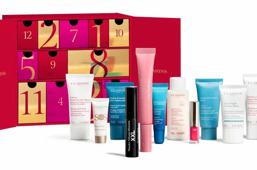 The Clarins 12 Day Beauty Advent Calendar 2026 open, with its lip, skincare and body care products lined up in front of the red and gold box