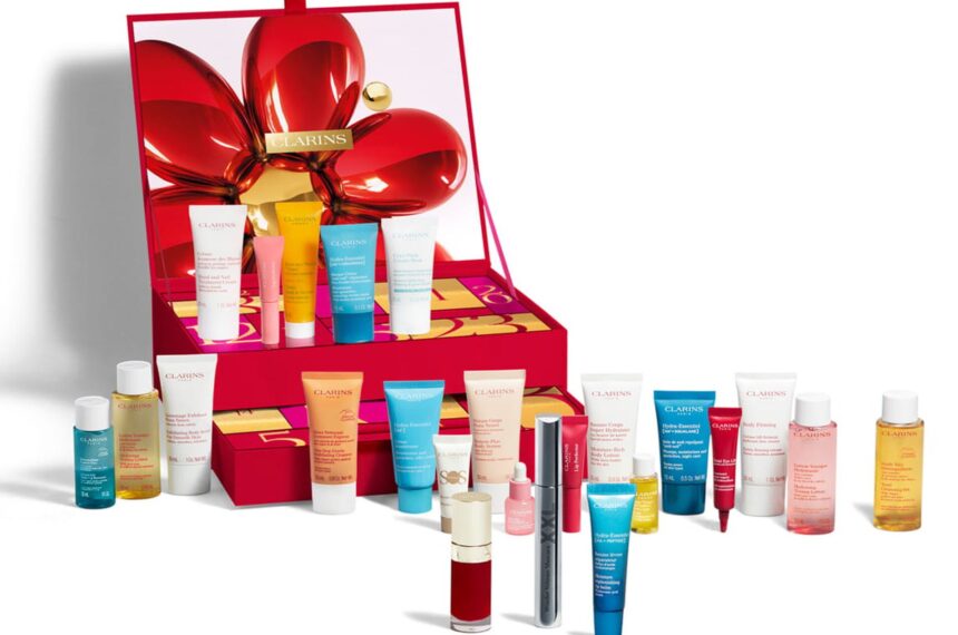 The Clarins 24 Day Beauty Advent Calendar 2026 open, with its skincare, body care and make-up products displayed in front of the red box