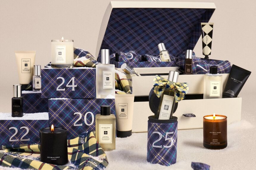 The Jo Malone Christmas Kist Advent Calendar 2026 trunk open among numbered crackers and tartan stockings, with colognes, body care and travel candles around it