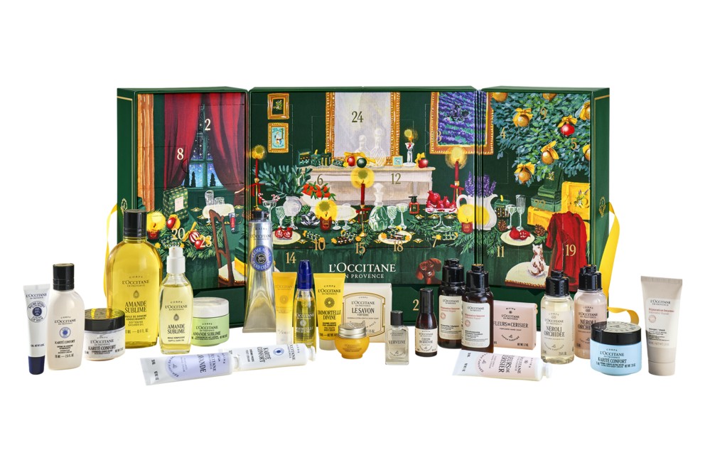 The L'Occitane Prestige Advent Calendar 2026 opened out to its illustrated interior, with its 24 products, including a large bottle of Almond Shower Oil, lined up in front