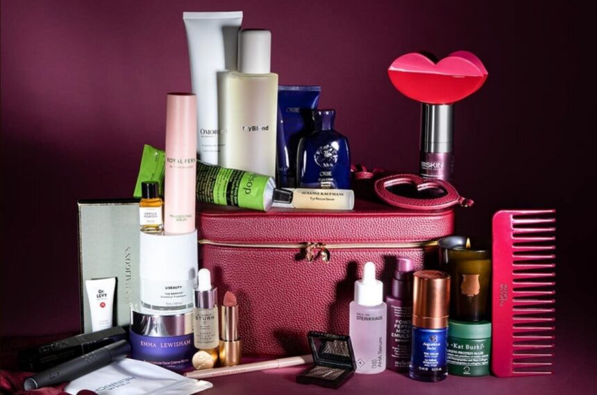 The burgundy Niche Beauty case with all the calendar products arranged around it, including a red lip-shaped hair clip, a cherry red comb, serums, creams and a candle