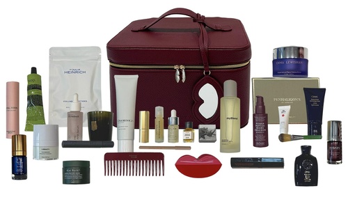 The burgundy Niche Beauty case in the centre with all 27 calendar products laid out either side, including a red comb, a lip-shaped clip, a candle, serums and creams