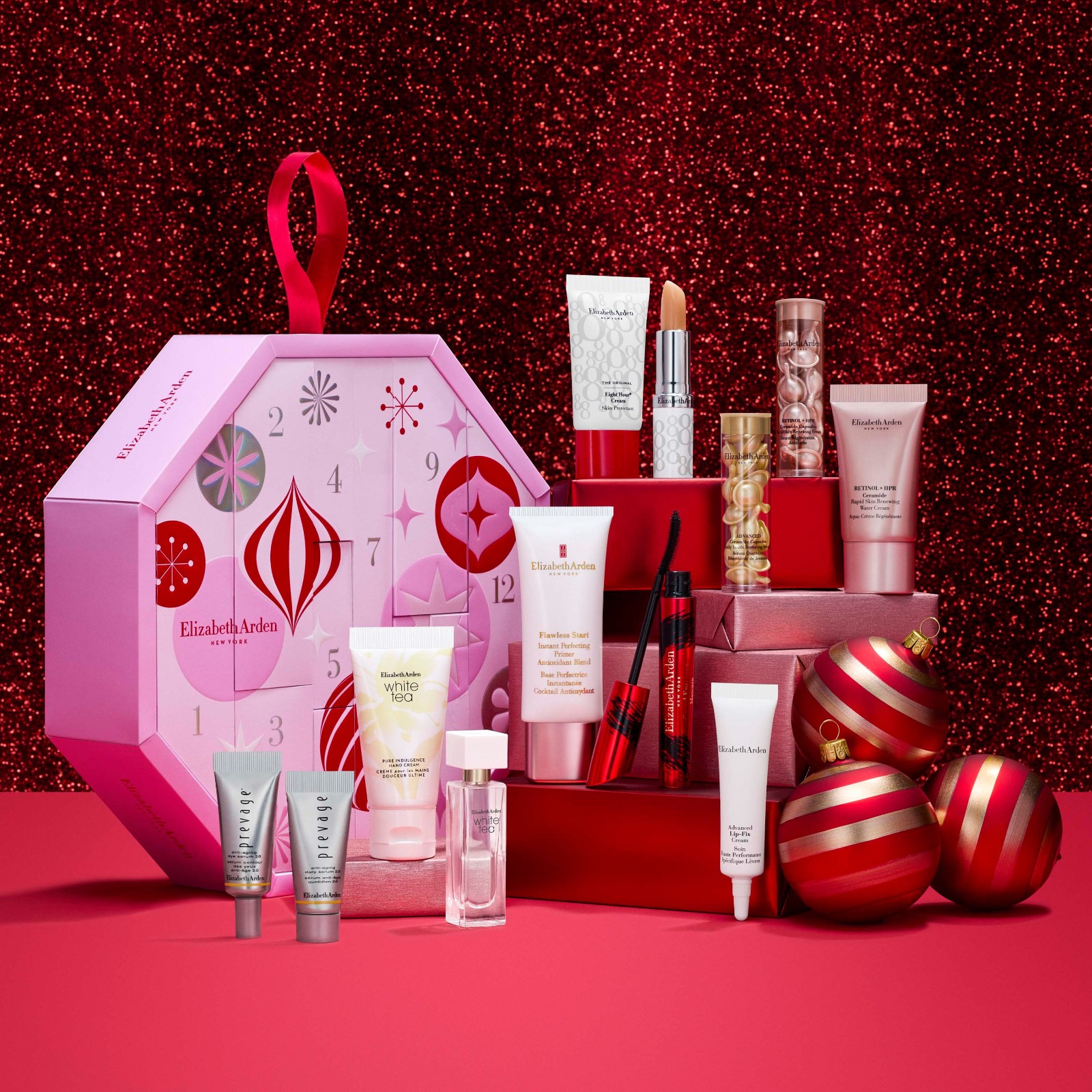 The Elizabeth Arden 12 Days of Beauty calendar open on a red set, with its skincare, makeup and fragrance arranged on pedestals beside it