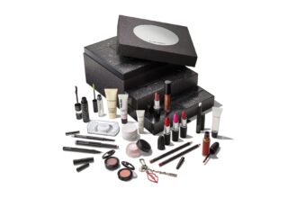 The 24 Days of M·A·C Icons Advent Calendar 2026, a black glittering box of stacked drawers with a mirrored lid, with its lipsticks, lip pencils, mascaras, eyeshadows, lashes and skincare minis set out in front